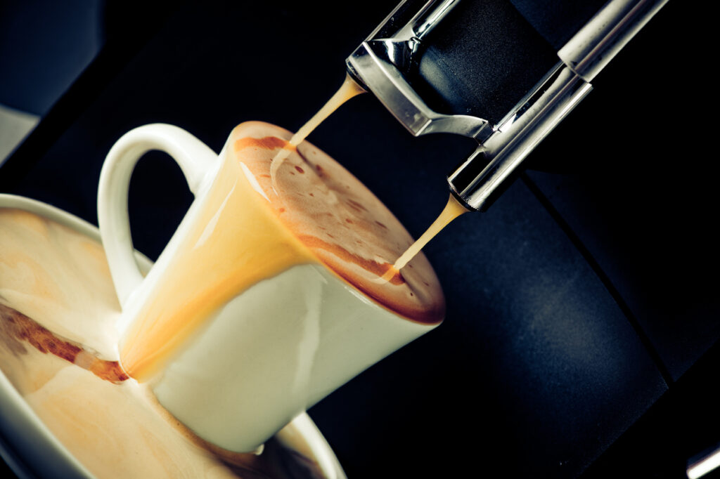 Overflowing coffee cup under the coffee-making machine
